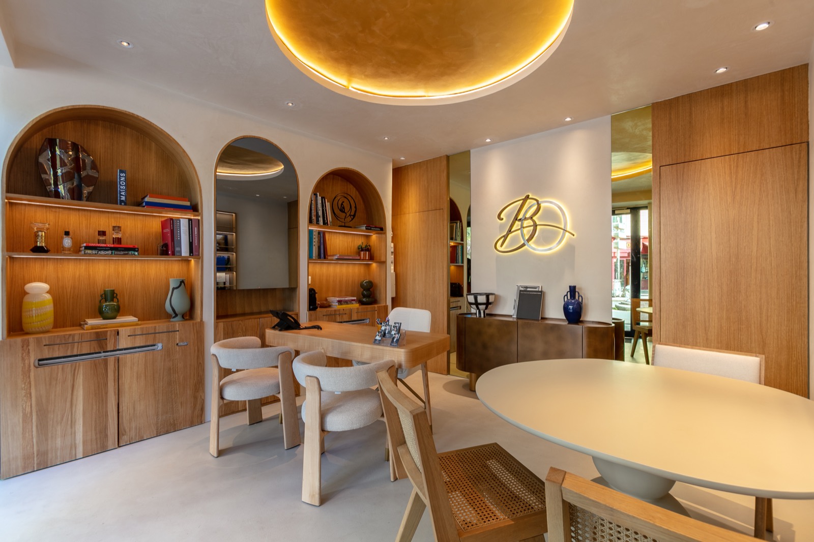 Intérieur de l'agence Bonjour Oscar Batignolles : enseigne lumineuse BO, mobilier bois et arches